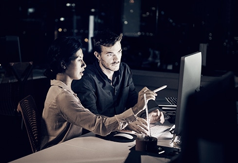 man and woman working at computer at night